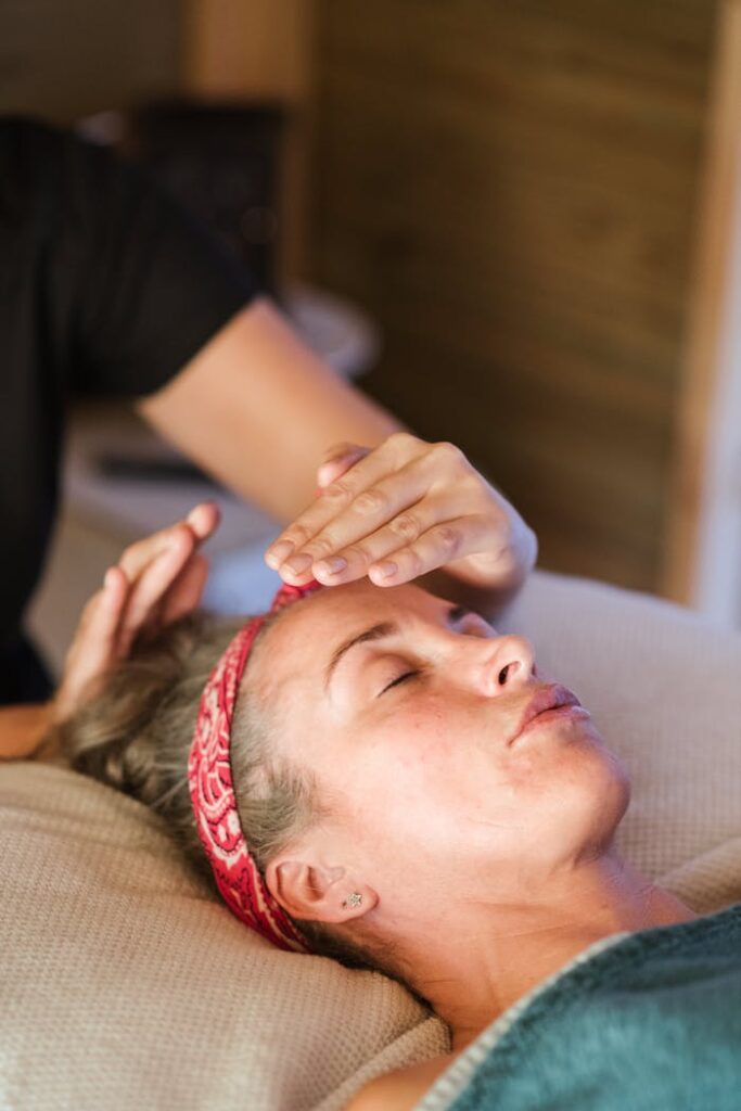 pexels-photo-5240733 A woman enjoying a peaceful reiki session in a cozy spa setting for ultimate relaxation.
